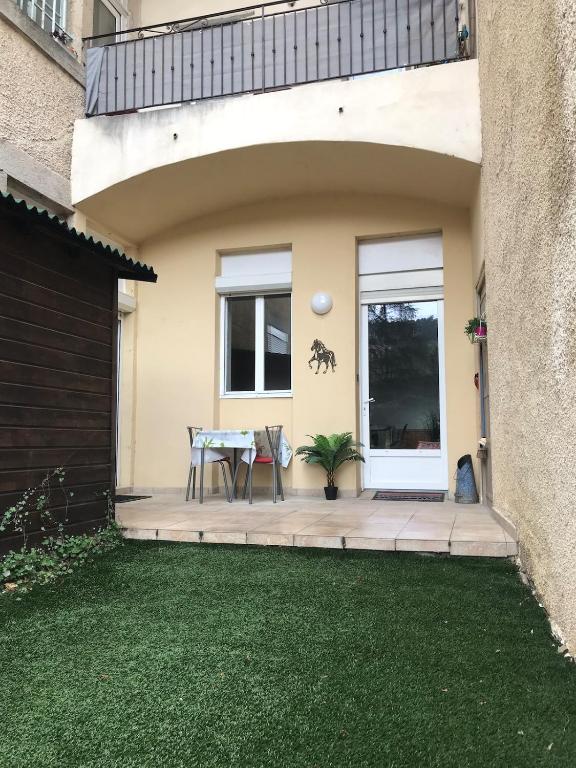 un patio avec une table devant une maison dans l'établissement bel appartement a vals les bains, à Vals-les-Bains