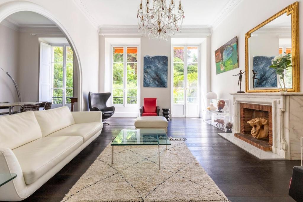 un salon avec un canapé blanc et une cheminée dans l'établissement Carré d'Or, superbe apartment sur jardin, élégant et ensoleillé, à Nice