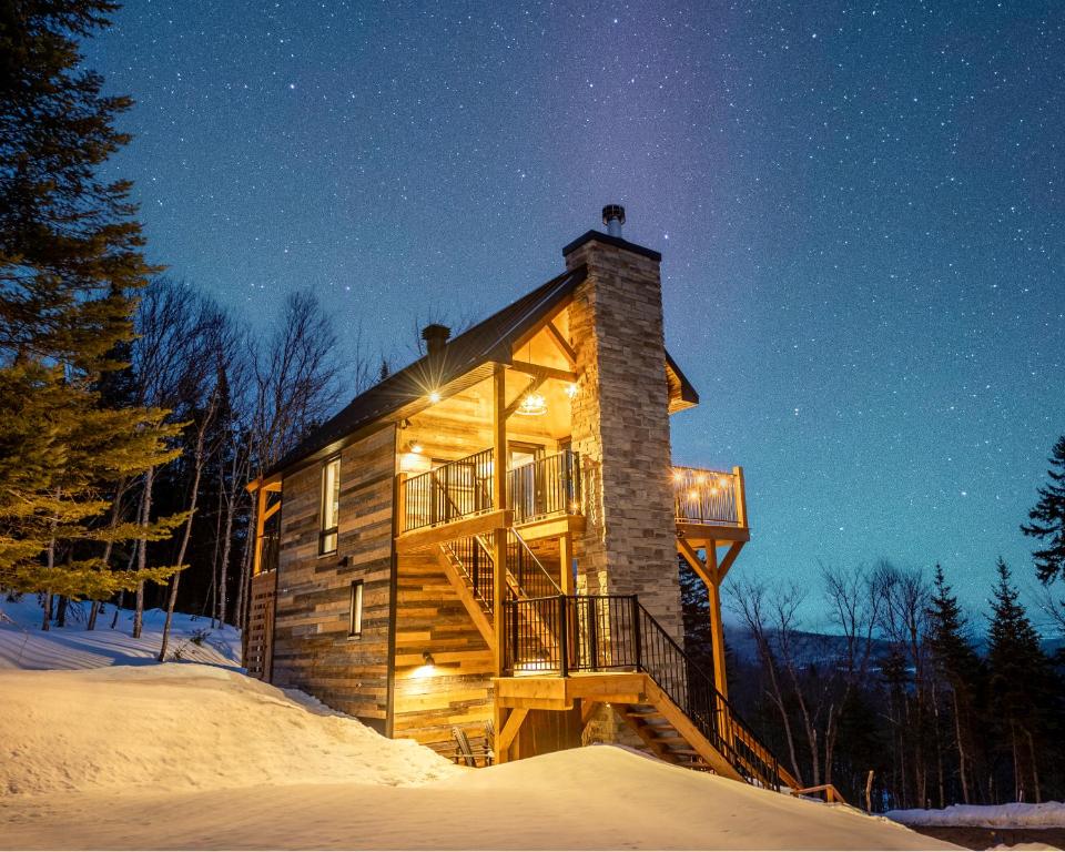 a log cabin in the snow at night at CHAMONIX - Micro Chalet with Panoramic Mountain Views near Québec in Lac-Beauport