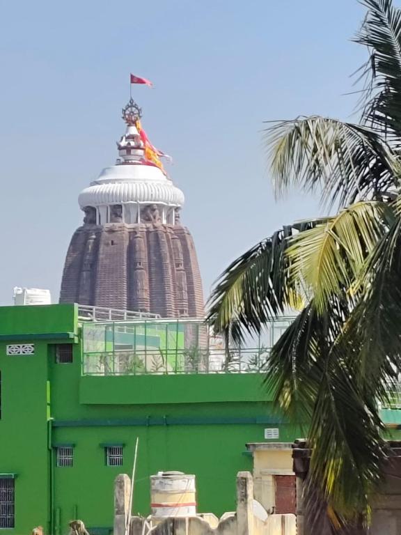 a green building with a tower on top of it at RS Homestay Puri in Puri