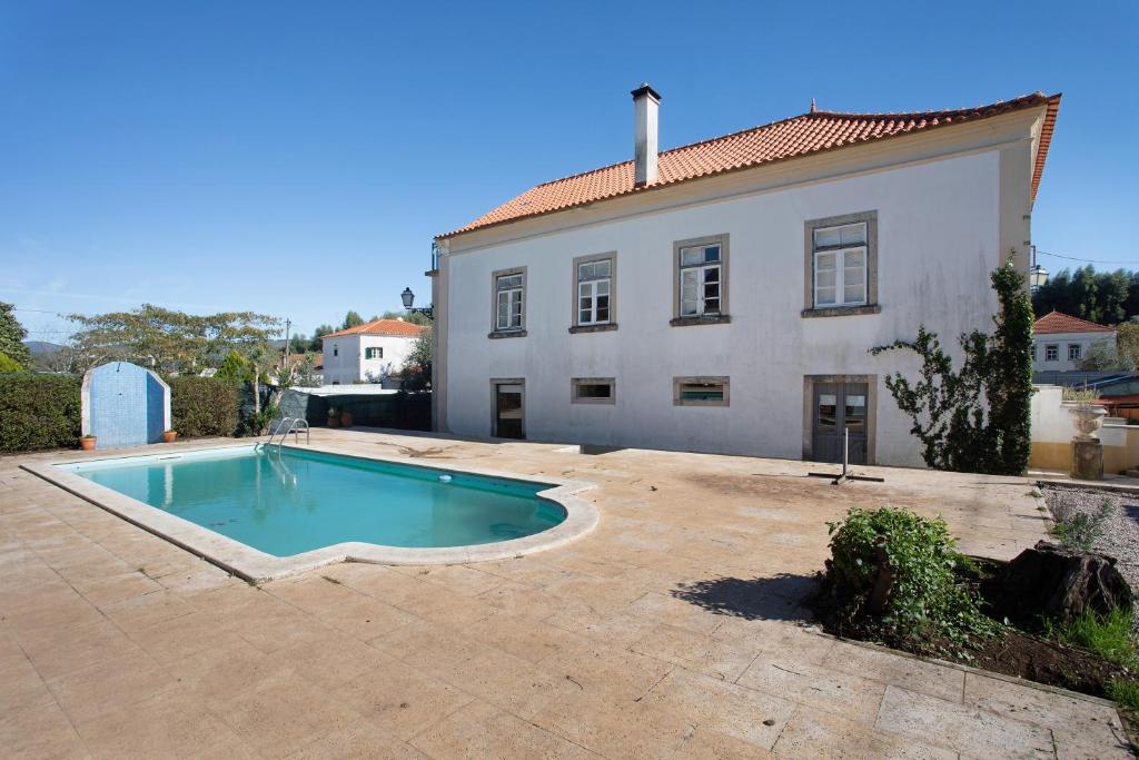 a swimming pool in front of a house at Casa das Camélias Tortas in Castanheira de Pêra
