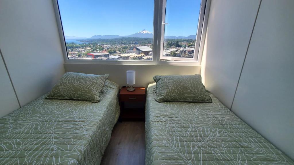 Departamento Mirador al Volcan في فيلاريكا: سريرين في غرفة صغيرة بها نافذتين