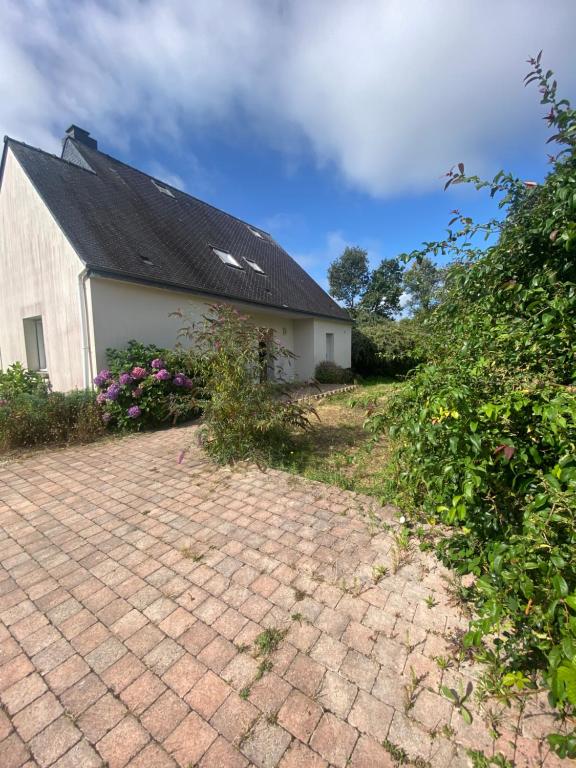 un bâtiment blanc avec un toit noir et une allée en briques dans l'établissement Maison de charme proche océan, à Lauzach