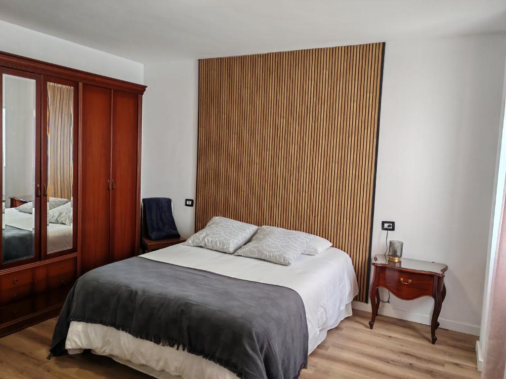 a bedroom with a bed and a wooden wall at Casa Rosales in La Orotava