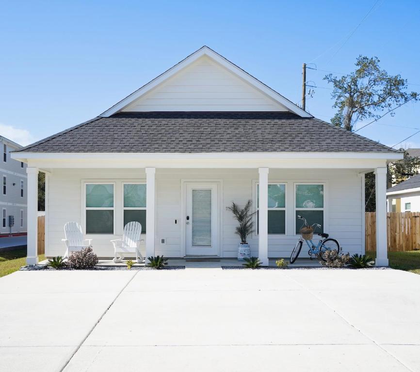 Casa blanca con 2 sillas blancas en la entrada en Walk to the beach Comes with two bikes, en Biloxi