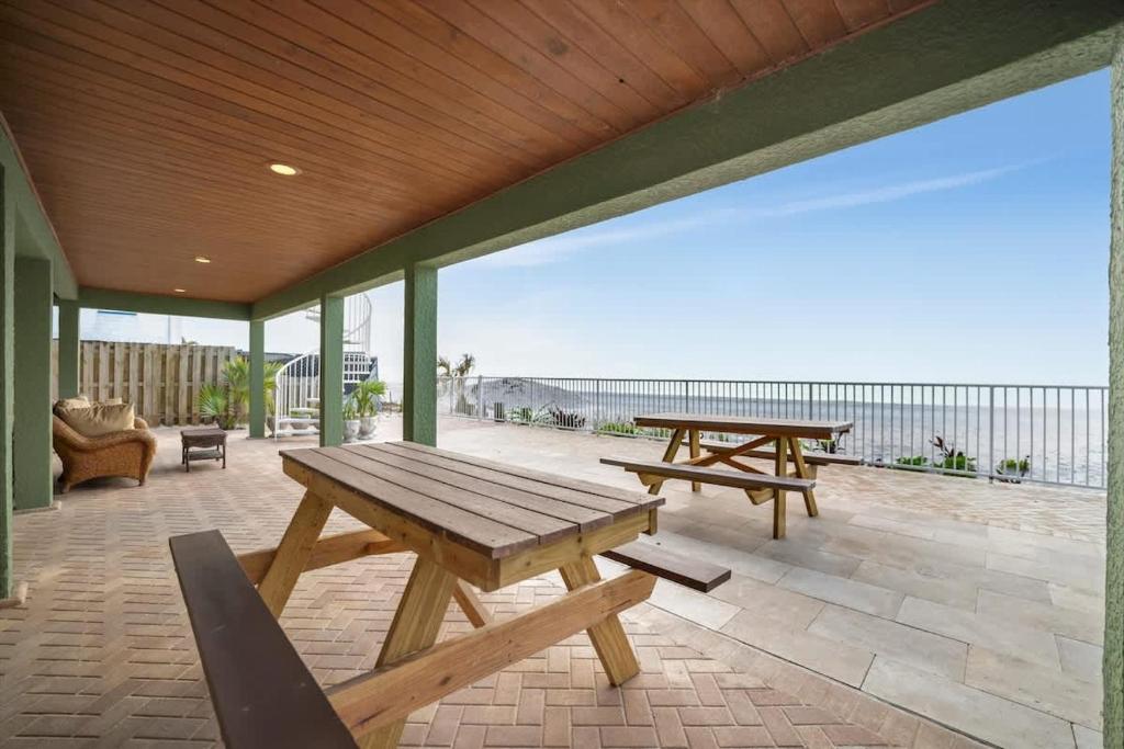 a picnic table and benches on a patio with the ocean at Stones Throw Beachside Bungalow #1 ON THE BEACH in Clearwater Beach