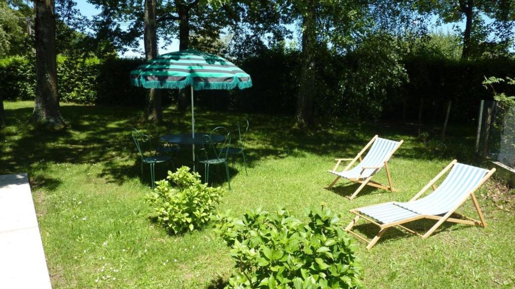 two chairs and an umbrella in a yard at Appartement L'Hivernelle in Capvern