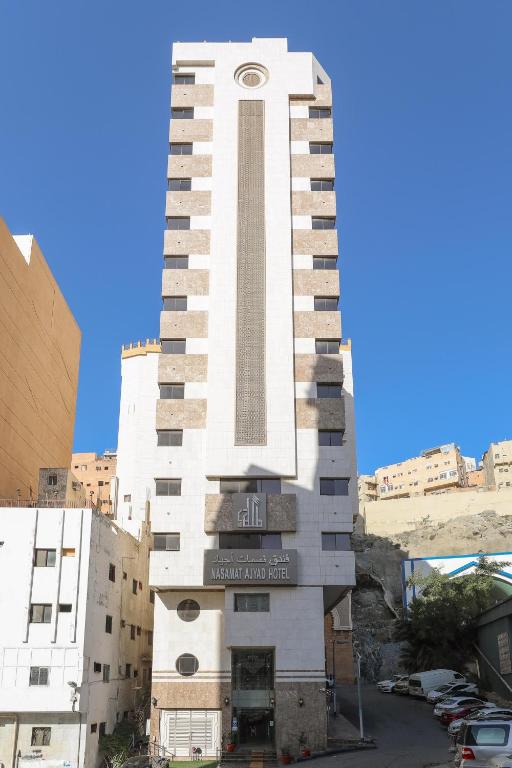 a tall white building with a clock tower at Nasamaat Ajyad Hotel in Mecca