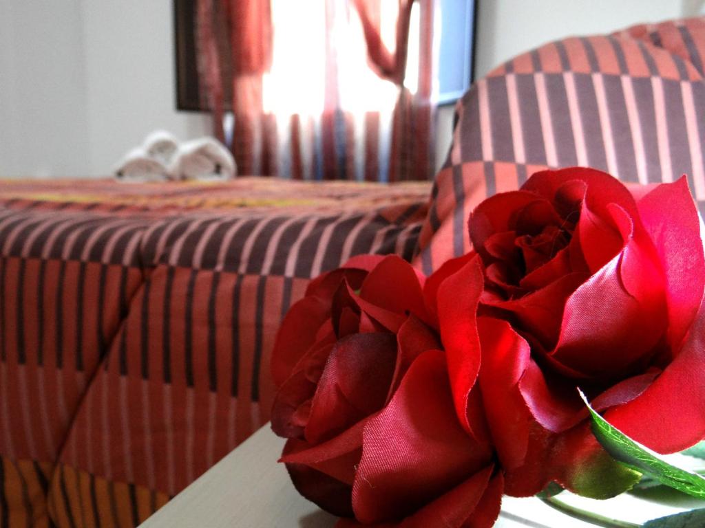 a red rose sitting on a table next to a bed at Le casette del generale in Trapani