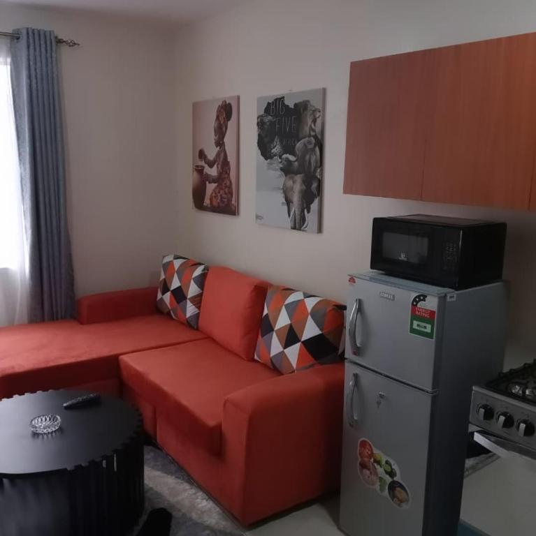 a living room with a red couch and a refrigerator at Maggies suites and Bnb in Nairobi