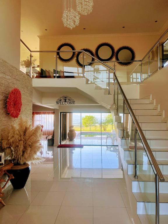 a staircase in a living room with a glass railing at Ambience on N2 Boutique Hotel in Kokstad