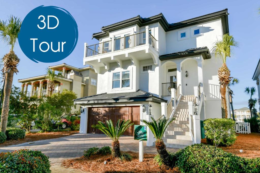 a large white house with palm trees and the words tour at Casa Di Amore in Destin