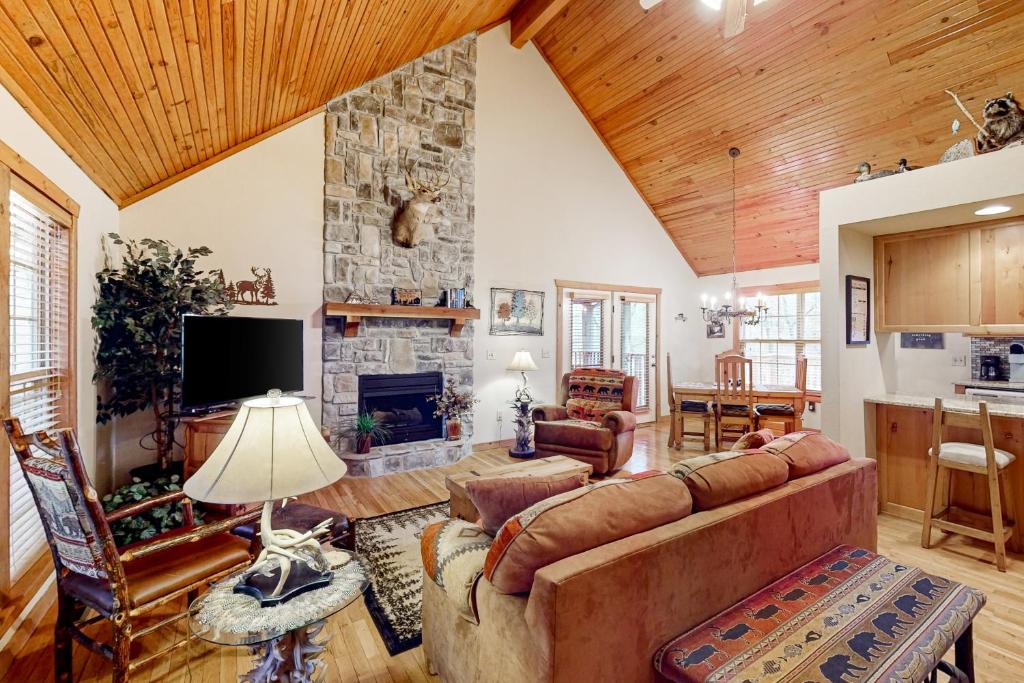 a living room with a couch and a stone fireplace at Lost Creek Haven in Branson West