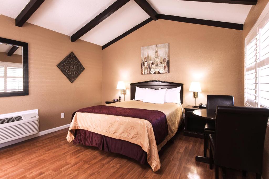 a hotel room with a bed and a desk and a bedroom at Tri-Valley Inn & Suites in Pleasanton