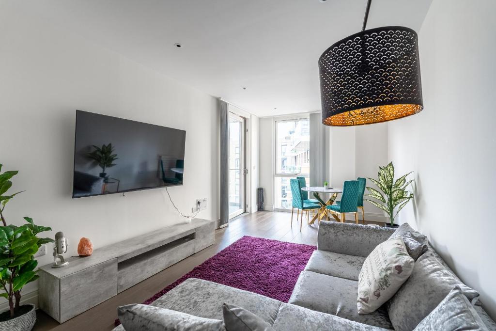 a living room with a couch and a tv on a wall at Modern & Cosy Flat in Kingston in Kingston upon Thames