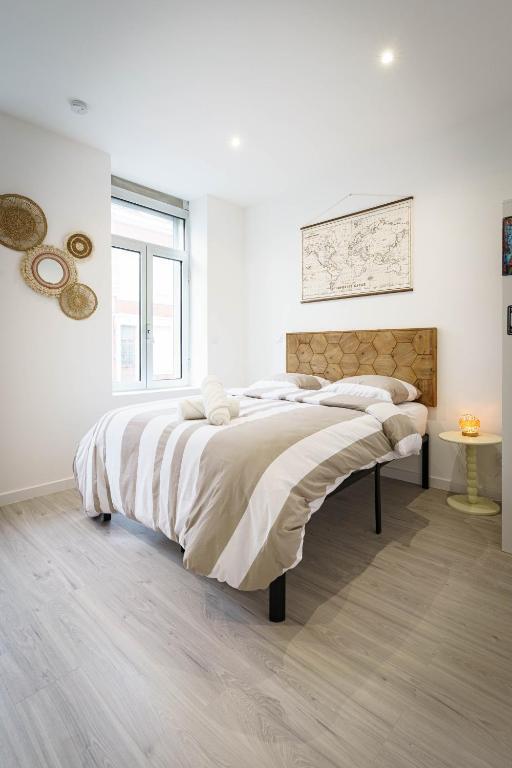 une chambre blanche avec un grand lit et une fenêtre dans l'établissement L'Audacieux De Longueville, à Saint-Quentin