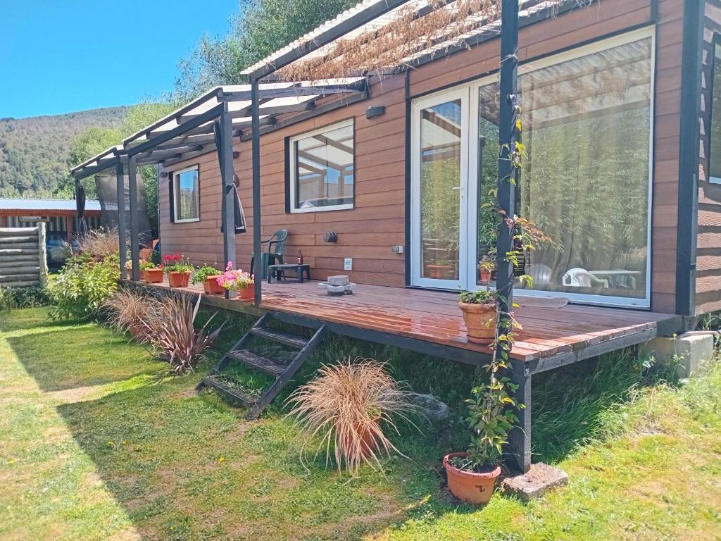 a cabin with a wooden deck with potted plants at El Vagon in San Martín de los Andes