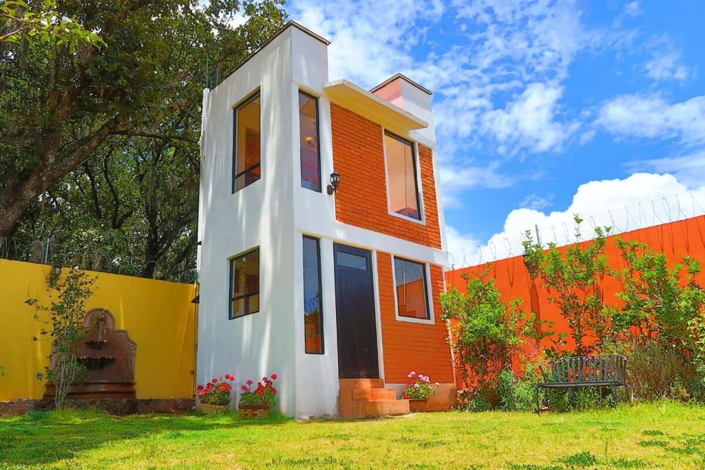 a house that is painted orange and white at Loft romántico y acogedor junto al bosque in Huasca de Ocampo