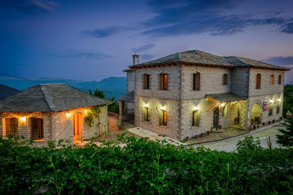 una gran casa de piedra con luces encendidas por la noche en Balkoni Zagoriou, en Vradéton