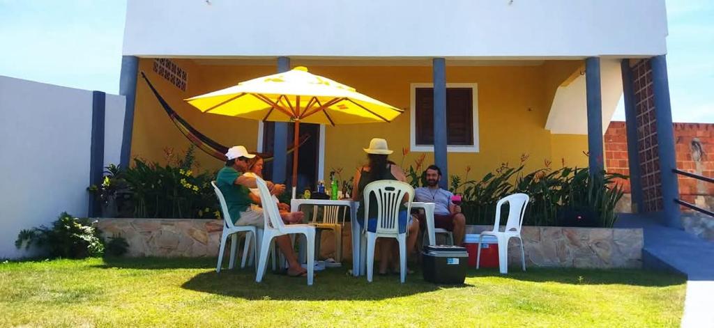 a group of people sitting at a table under an umbrella at Chalés Luz do Luar in Aracati