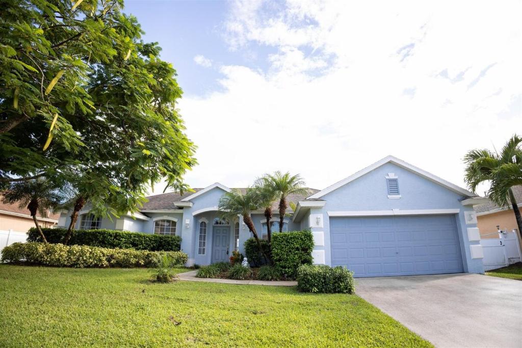 a house with a garage and palm trees at A Home Where Memories Are Made in Port Saint Lucie
