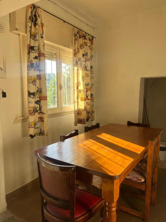 a wooden dining room table with chairs and a window at Los Lirios Gardes Pehuajo in Pehuajo