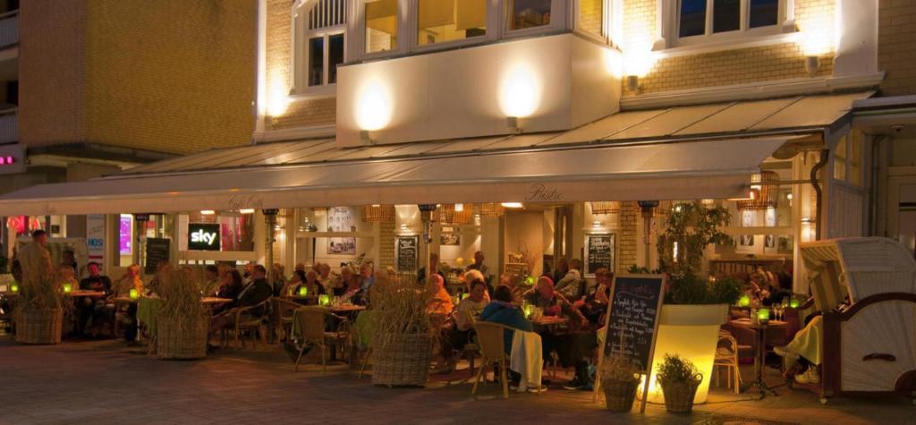 um grupo de pessoas sentadas num restaurante à noite em Café Orth em Westerland