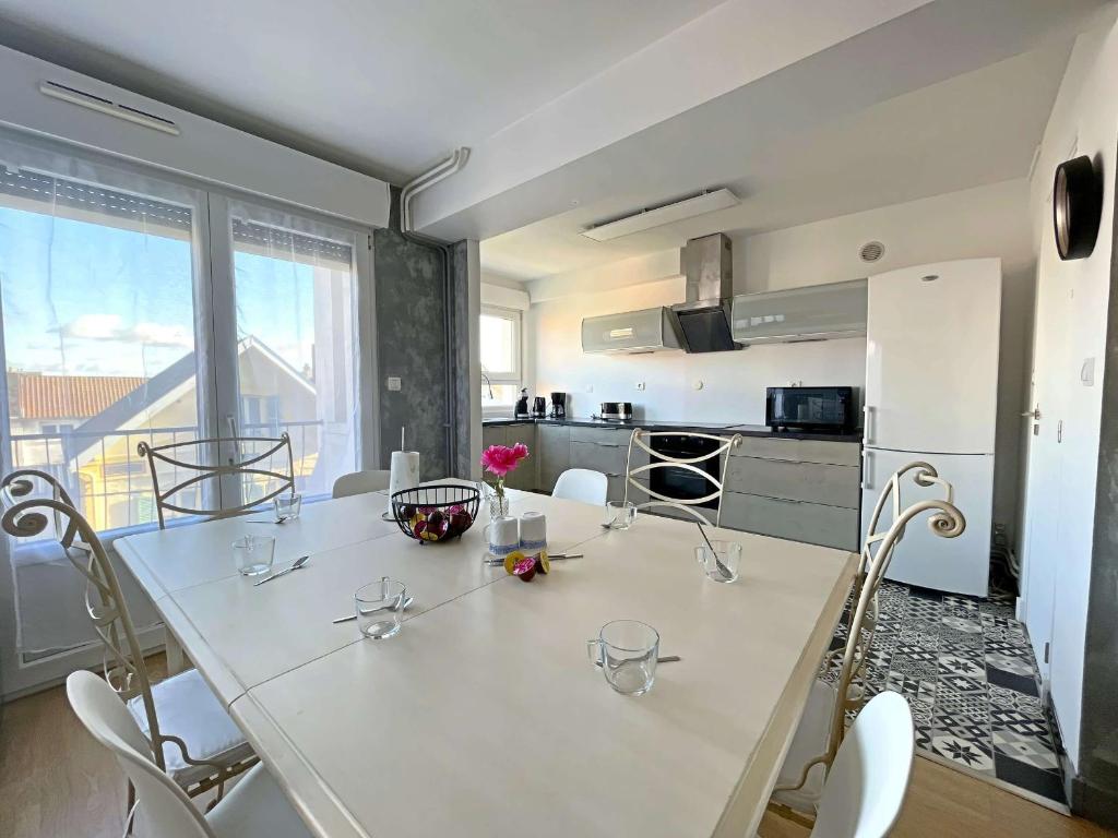 une cuisine avec une grande table blanche et des chaises dans l'établissement Appartement spacieux au cœur de Berck-Plage avec balcon et parking - FR-1-646-82, à Berck-sur-Mer