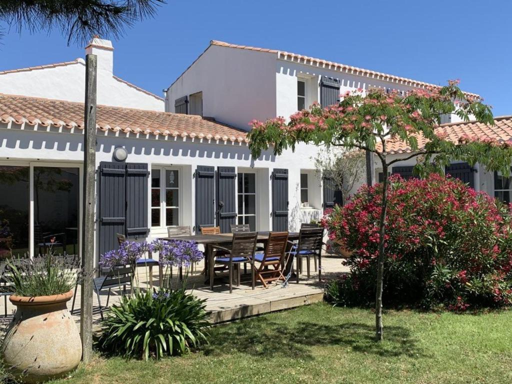 une maison avec une table et des chaises dans la cour dans l'établissement Belle maison 6 pièces proche plage à La Guérinière - FR-1-224B-239, à La Guérinière