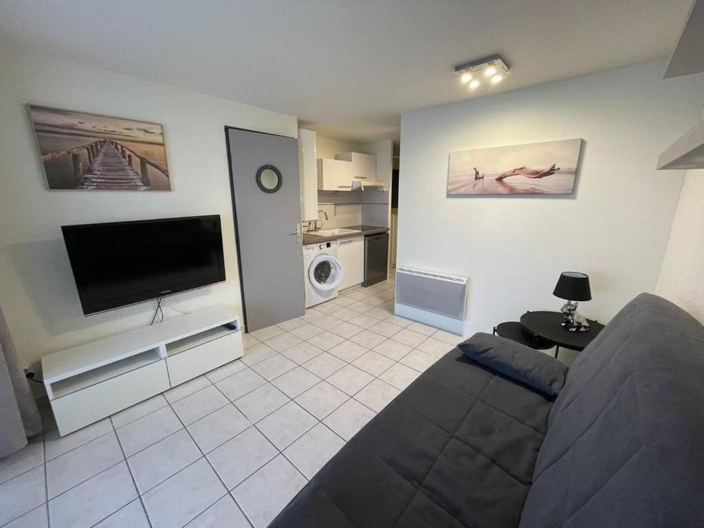 un salon avec un canapé et une télévision à écran plat dans l'établissement Appartement rénové à 300m de la plage avec parking - FR-1-723-170, au Cap d'Agde