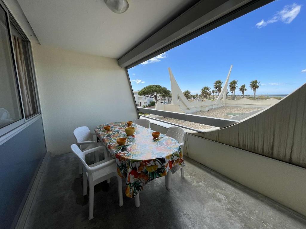une table et des chaises dans une pièce avec une grande fenêtre dans l'établissement Appartement avec piscine, animaux admis, parking, plage à Port Camargue, 4 pers. - FR-1-250-296, au Grau-du-Roi