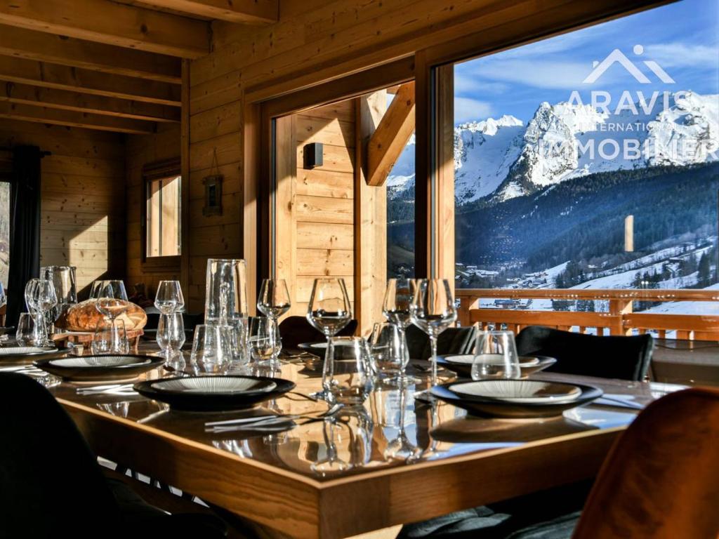 a table with wine glasses and a view of a mountain at Chalet au Grand Bornand – 6 Chambres Spacieuses & Ambiance Chaleureuse - FR-1-391-194 in Le Grand-Bornand