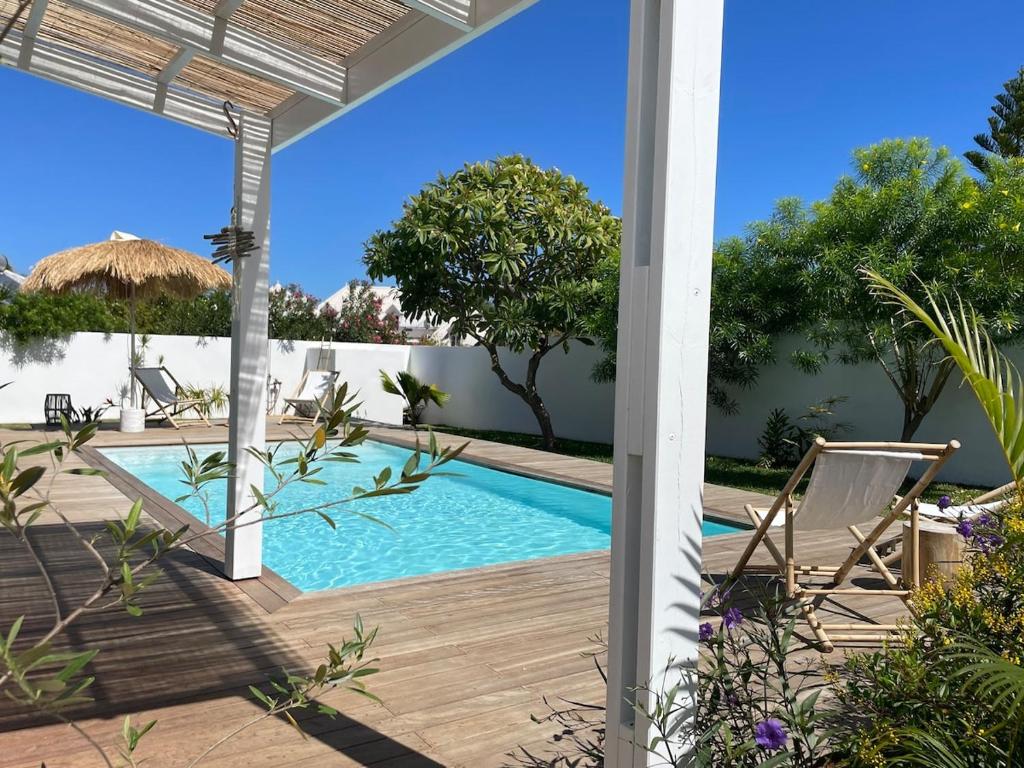 サンジルレバンにあるVilla de charme près des plagesの家の隣にデッキと椅子付きのスイミングプールがあります。