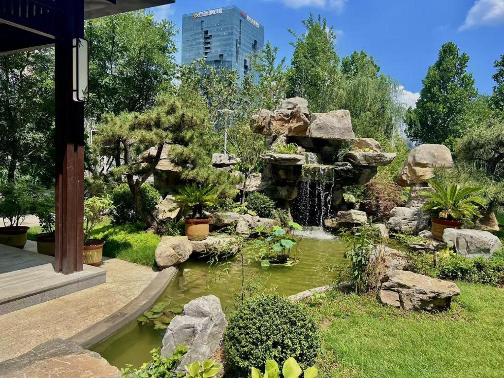 um jardim com um lago e uma cascata em Century Runhua Hotel em Jinan