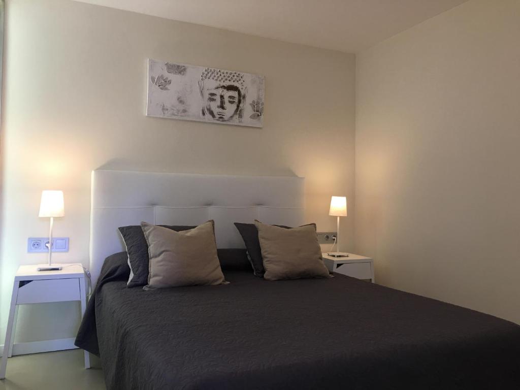 ein Schlafzimmer mit einem schwarzen Bett und zwei Nachttischen in der Unterkunft Studios Coll, Terrace & Pool in Sant Martí d’Empúries