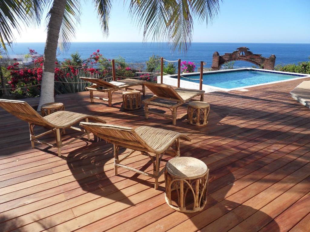 eine Terrasse mit Stühlen, einen Pool und das Meer in der Unterkunft Villa Casa Blanca del Faro in Zipolite