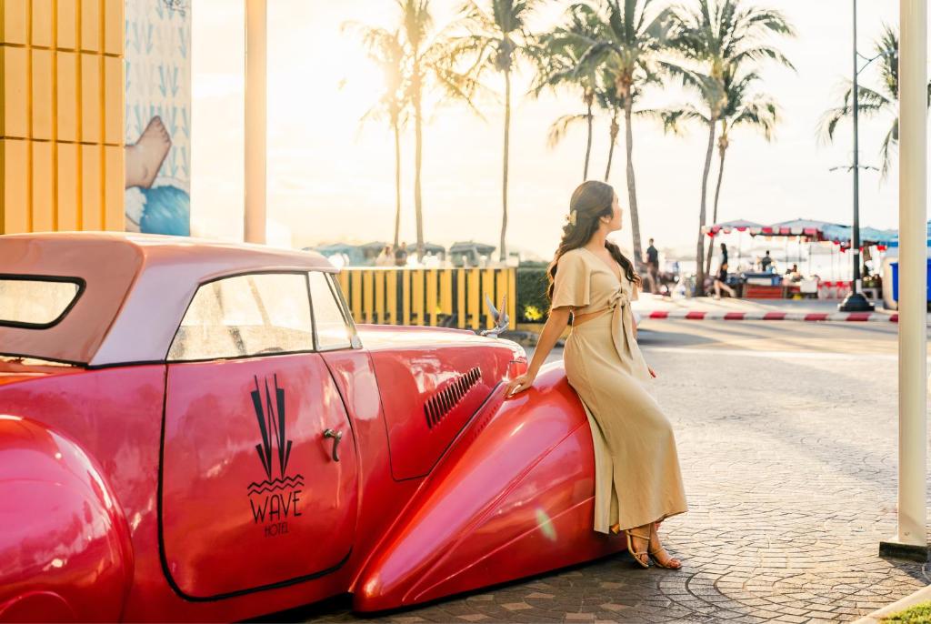 a woman is standing next to a red car at Wave Hotel Pattaya in Pattaya