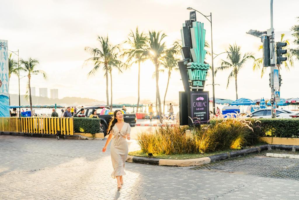 a woman walking down a street with palm trees in the background at Wave Hotel Pattaya in Pattaya