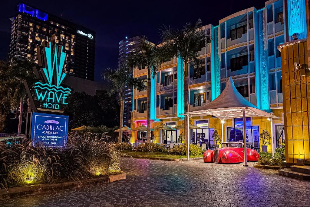 a hotel with a car parked in front of a building at Wave Hotel Pattaya in Pattaya