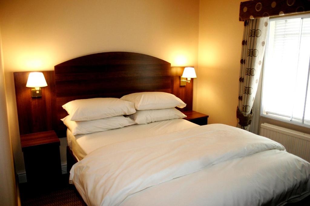ロンドンにあるザ レイルウェイ タバーン ホテルのベッドルーム1室(大型ベッド1台、白いシーツ、枕付)