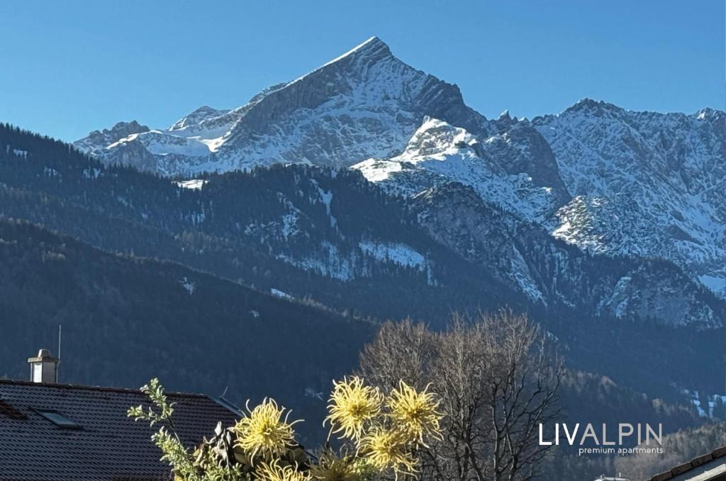 a snow covered mountain in front of a house at LIVALPIN Style in Garmisch-Partenkirchen