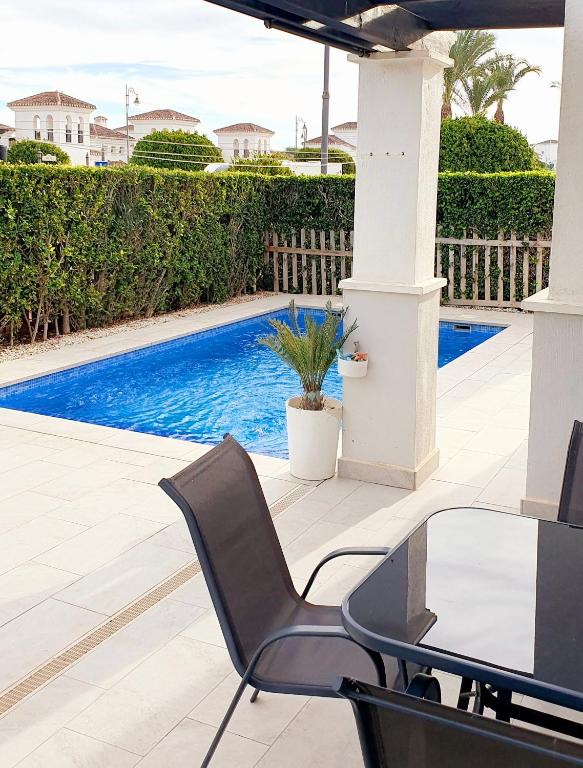 a patio with a table and chairs next to a swimming pool at Villa mit privatem Pool, zentrumsnah in Roldán