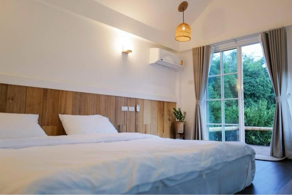 um quarto com uma grande cama branca e uma janela em อาข่า พามิโอ้ em Ban Pha Mi