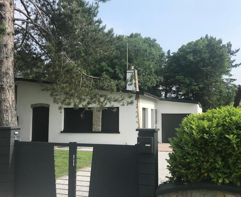 une maison blanche avec des portes noires et une clôture dans l'établissement Villa Stella plage proche Le Touquet pour 6ou8 personnes, à Cucq