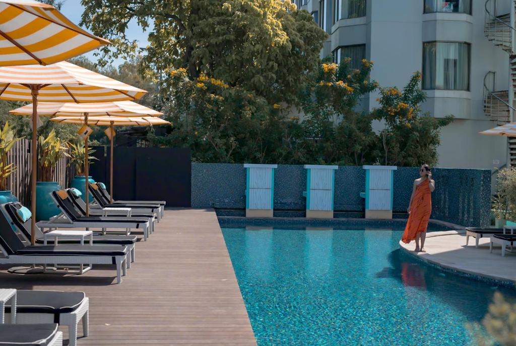 a woman in a dress standing next to a swimming pool at Wave Hotel Pattaya in Pattaya