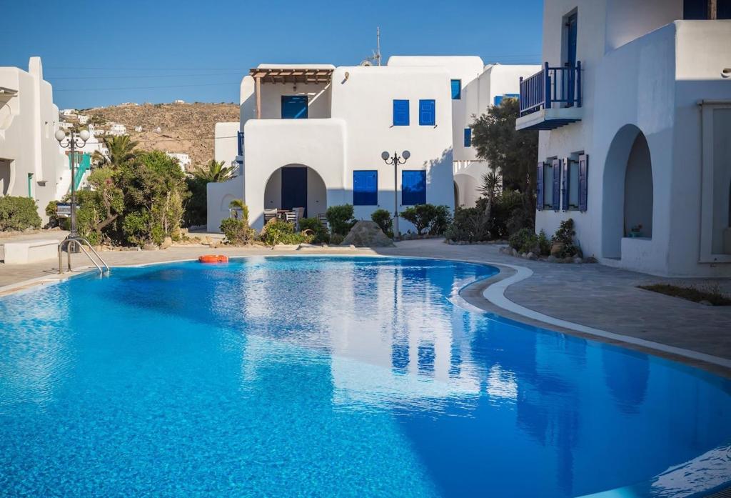 una piscina con acqua blu di fronte agli edifici bianchi di Villa Iliana 1 & 2 w shared Pool, Ornos, Mykonos a Ornos