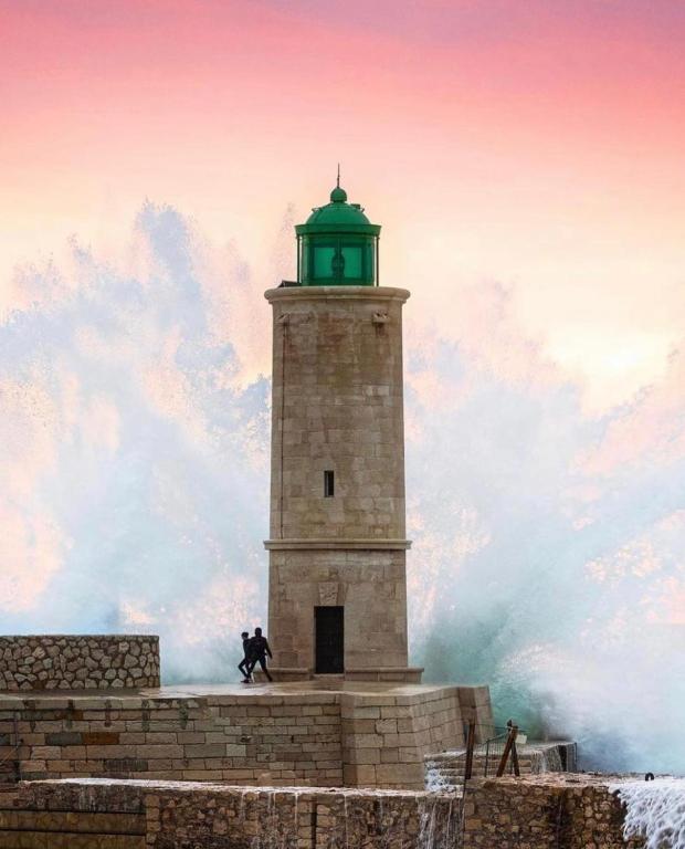 un phare avec un homme courant devant lui dans l'établissement La Cassy - Sleep in Cassis, à Cassis