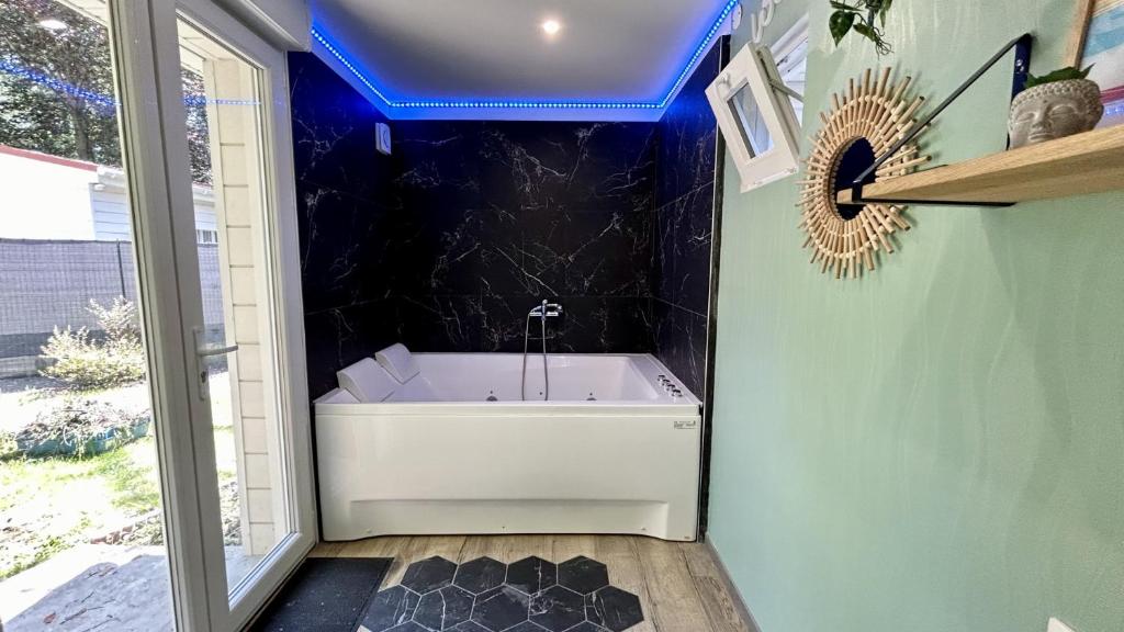 a bathroom with a tub with a blue ceiling at Terre & Mer'veilles 2, appartement avec SPA pour 2 personnes in Favières