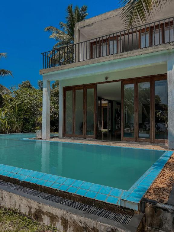a swimming pool in front of a house at Red Mangrove in Bentota