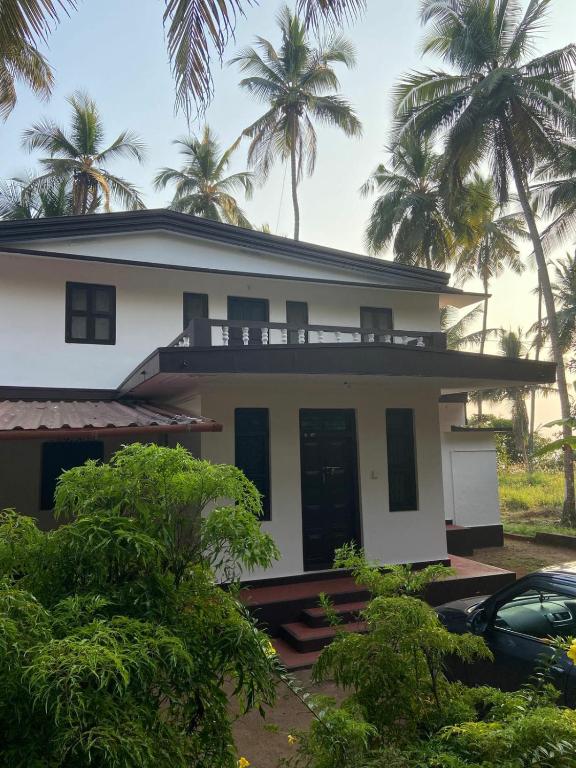 a white house with palm trees in the background at Casa Shanti in Kannur